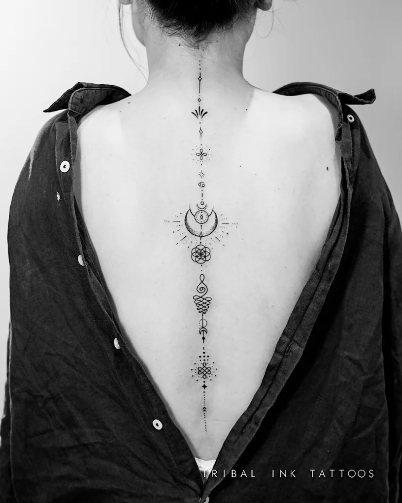 An ornamental column of fine-line symbols, crescents and dotwork running down a woman's spine.